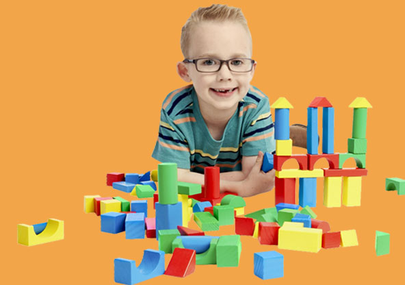 Young, happy boy playing with colorful building blocks