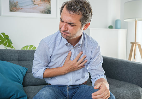 Man with acid reflux on couch, holds his chest questioning if GERD is curable.