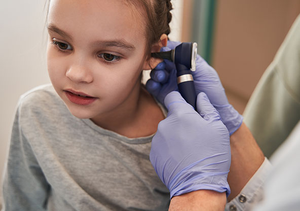 Girl sits quietly and waits for ear exam by pediatrician to end.