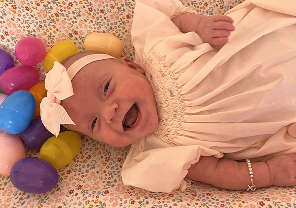 New baby Lily Speckman, smiling at the camera with a pink bow on. Lily spent 101 days in the NICU.