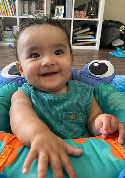Baby Perseus is smiling in his bouncy chair at home