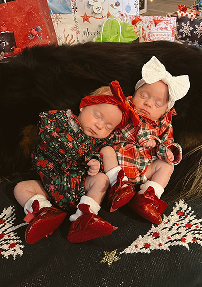 Baby Cambrie and baby Scout are in their holiday outfits, sleeping on a beanbag.