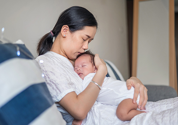 A mom holding her new baby who is sleeping on her chest