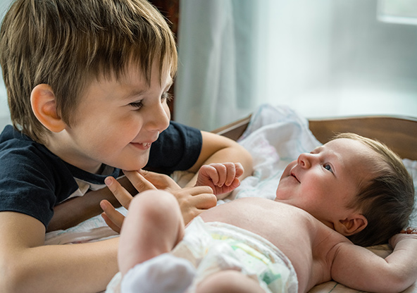 A young boy smiles at his new baby sibling