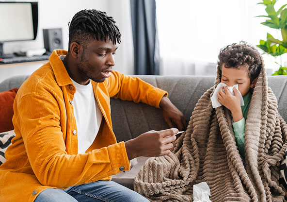 A dad reads a thermometer after taking his son's temperature