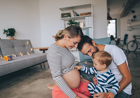 Happy family looking at pregnant mom's tummy