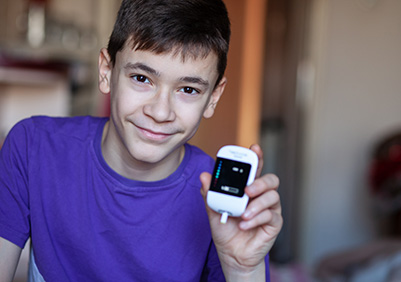 Tween holding up his blood glucose monitor