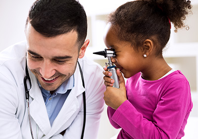 Young girl using an otoscope to look in the doctor's ears